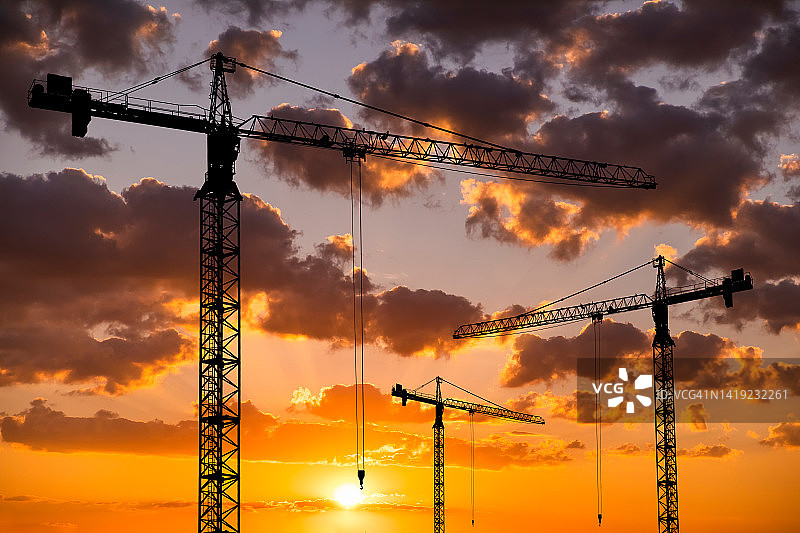 夕阳下的建筑工地与起重机：公寓楼建造图片素材