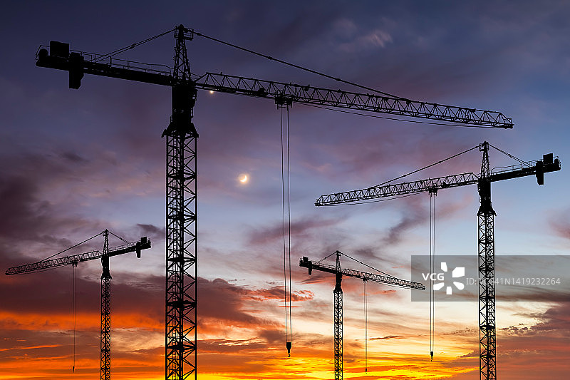 夕阳下的建筑工地与起重机：公寓楼建造图片素材