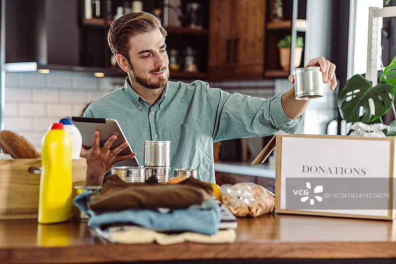 微笑的男人在捐赠箱中整理和打包物品图片素材