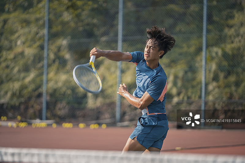 技术娴熟的年轻中国男子网球运动员在硬地球场打网球图片素材