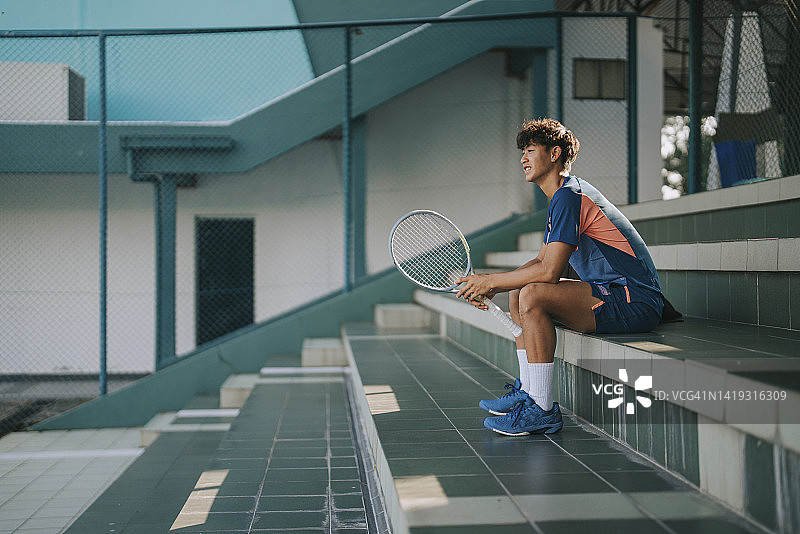 清晨坐在体育场网球场上的亚裔华人职业网球男运动员图片素材