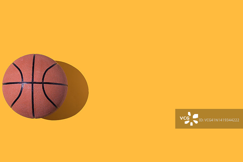 黄色背景上的橙色篮球：运动与比赛图片素材
