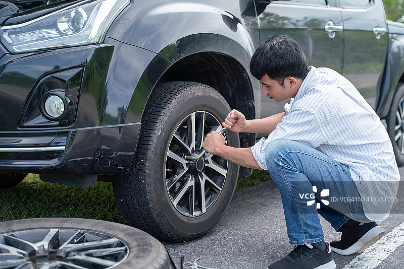 男人在汽车抛锚后更换轮胎，交通运输概念图片素材
