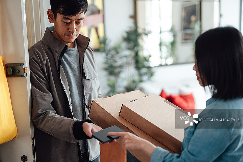 年轻女人使用智能手机签收包裹图片素材