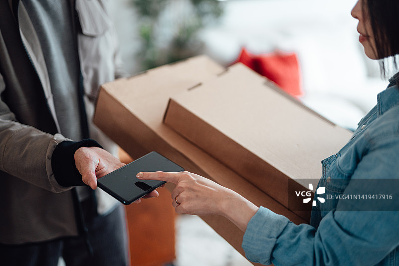 年轻女人使用智能手机签收包裹图片素材