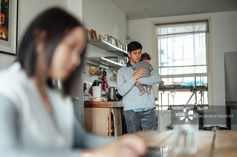 年轻父母在家工作时照顾宝宝图片素材