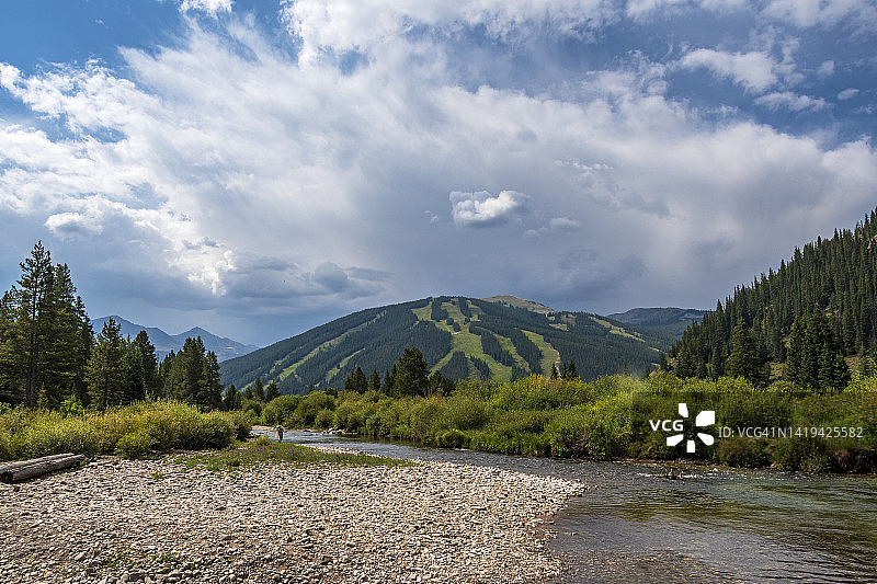在科罗拉多的十英里小溪里用飞蝇钓鱼的老年妇女图片素材
