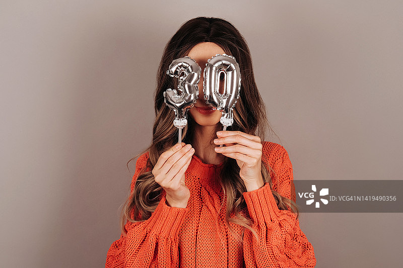 年轻女人用数字气球遮挡面部图片素材