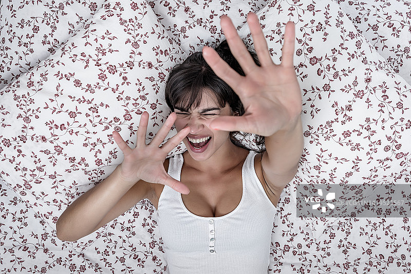 在床上做出停止手势的表情丰富的女人图片素材