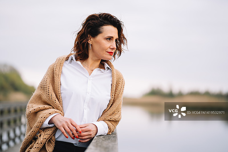 独自在秋日公园漫步的中年妇女图片素材