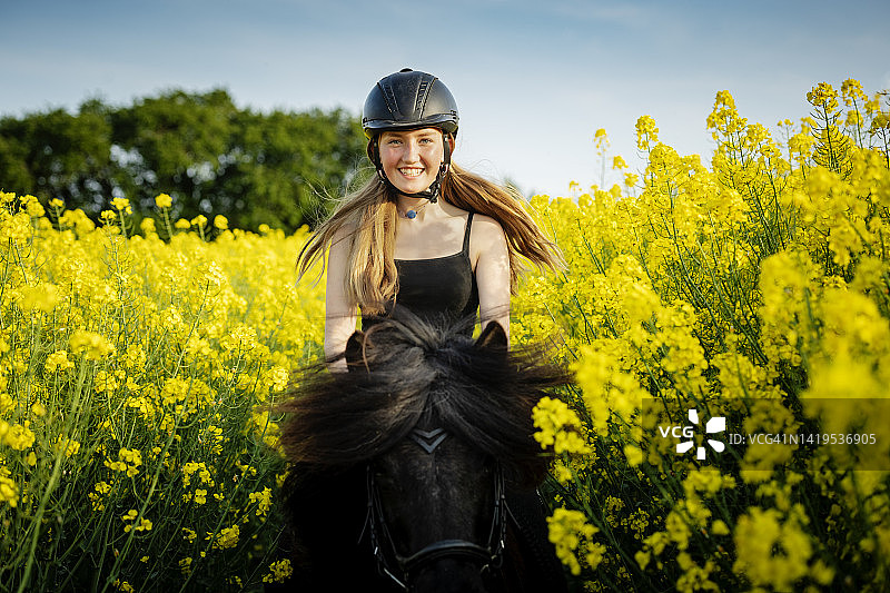 骑马穿过油菜花田图片素材