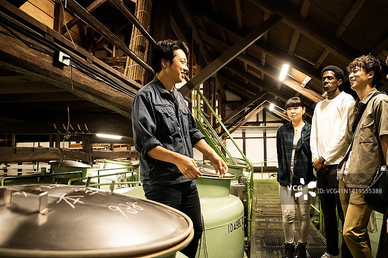 工匠带领游客参观日本的清酒酿酒厂图片素材