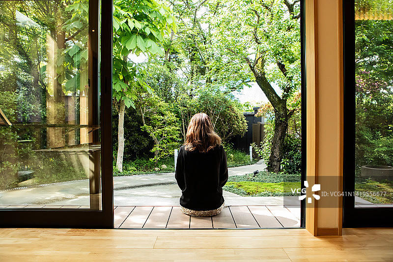 在日本旅行期间，在宾馆门廊放松身心的女游客的背影图片素材