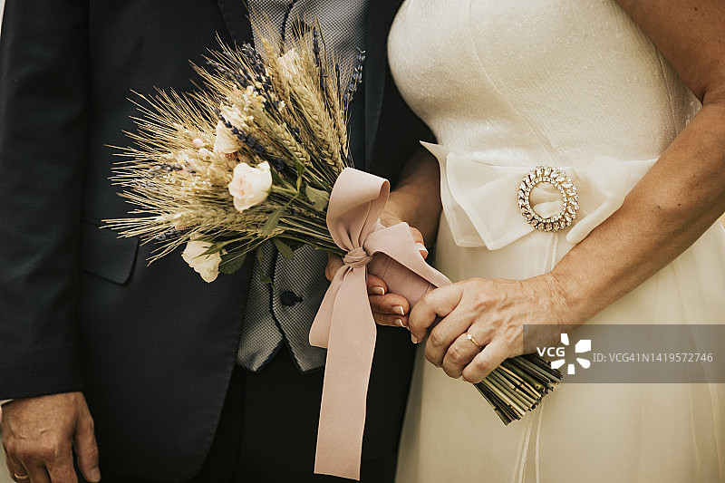 新娘手持婚礼花束时，新婚夫妇的手图片素材