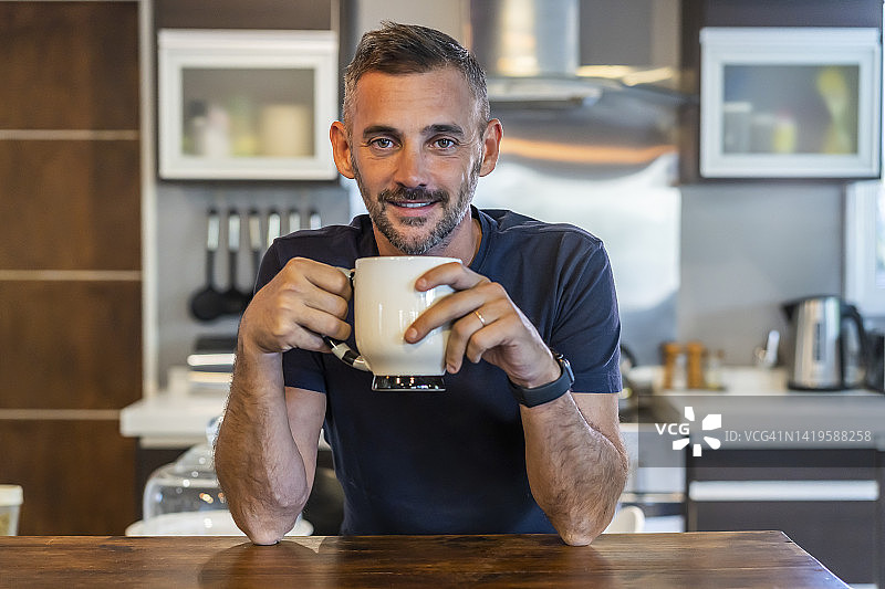 一位英俊的男人一边喝咖啡一边看着镜头图片素材