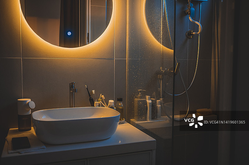 温暖光线下的舒适浴室内部，带镜面反射和水槽图片素材