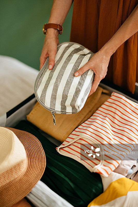 一位女士将化妆包放入手提箱的局部照片图片素材