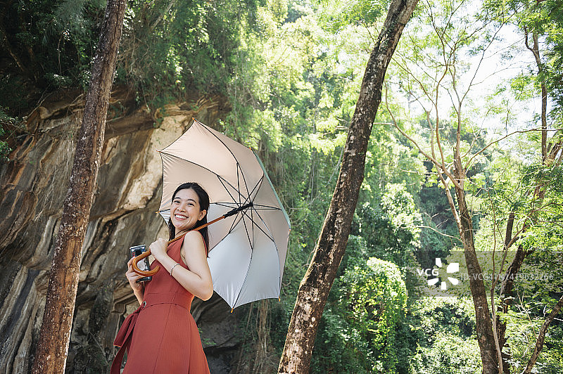 在东南亚热带森林中，使用紫外线防护伞遮挡酷热天气的亚洲女游客图片素材