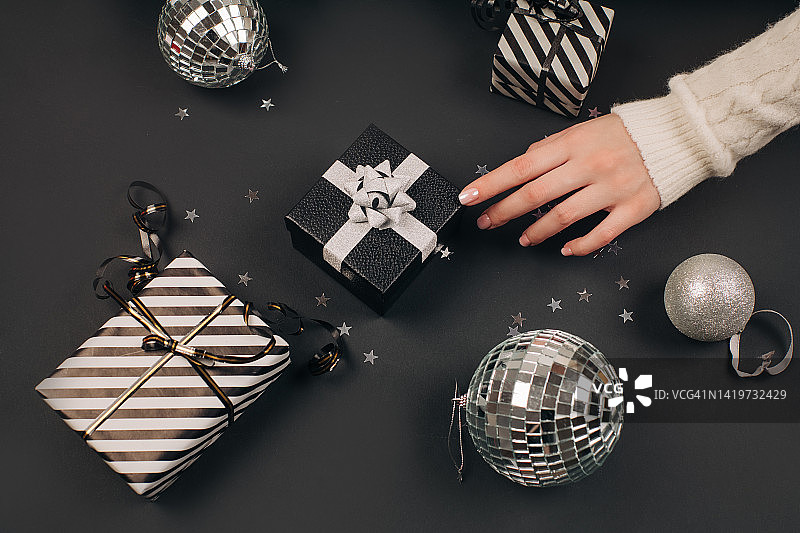 手持黑色礼品盒（金色丝带蝴蝶结，黑色背景）第一人称俯视照片图片素材