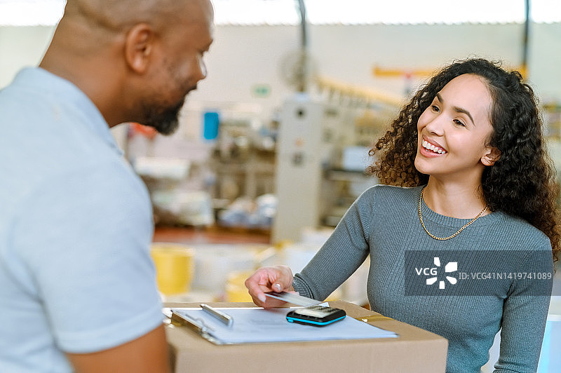 客户收货，信用卡支付以及快递员运送包裹给快乐的收货女士。通过便捷的射频识别交易处理款项图片素材