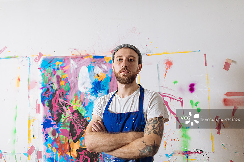 在彩色绘画作品前的表情严肃的艺术家图片素材