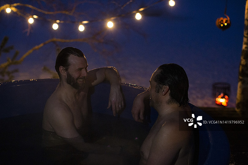快乐的赤膊中年男人在热水浴缸里聊天图片素材