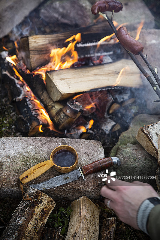 男子在篝火旁烤香肠图片素材