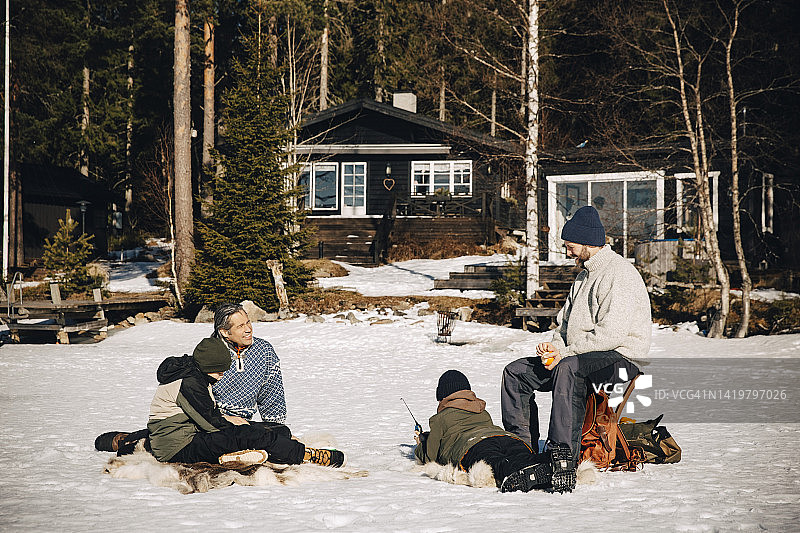 在阳光明媚的日子里，面带微笑的中年男人和男孩们在雪地里冰钓图片素材