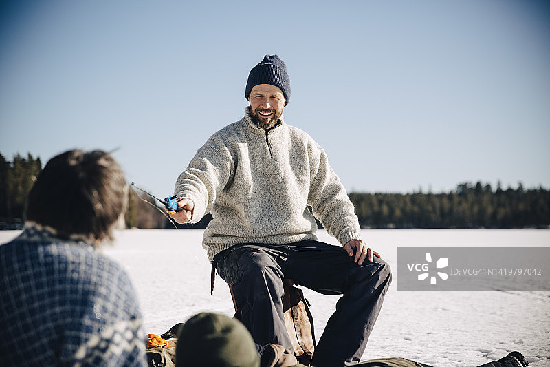 晴天里微笑的中年男人给朋友鱼竿图片素材