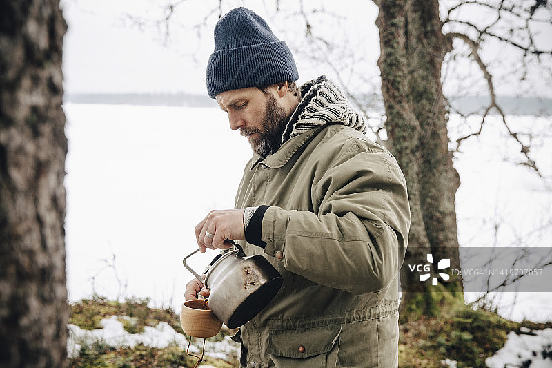 穿着保暖服装、用茶壶倒茶的年长男人图片素材