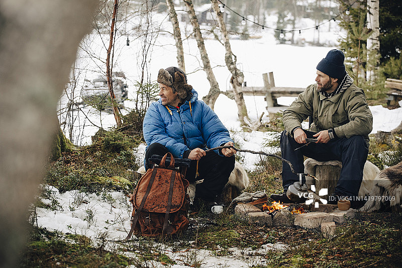 中年男人与朋友坐在篝火旁准备茶饮图片素材
