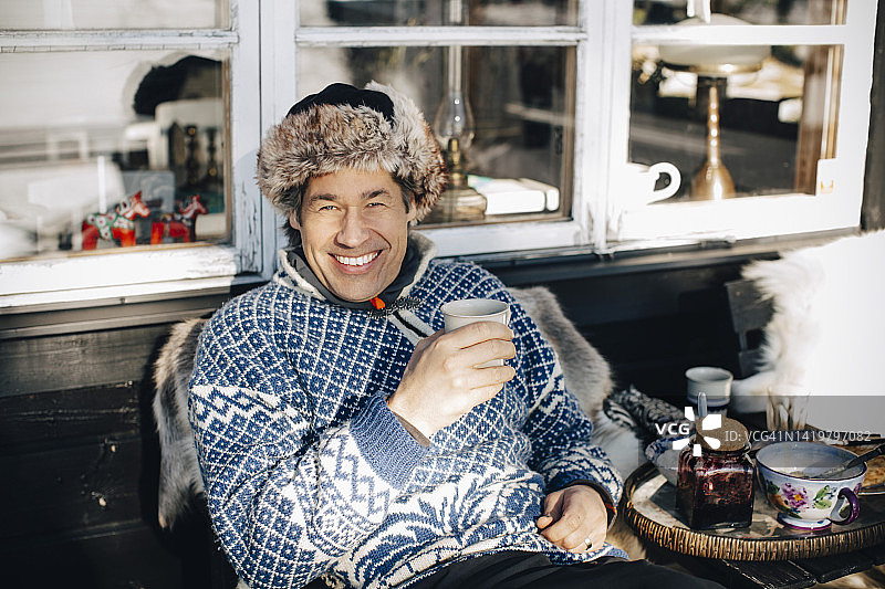 冬季坐在门廊喝咖啡的快乐成熟男士肖像图片素材