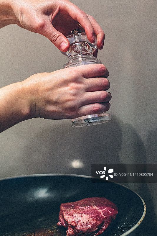在牛排上研磨胡椒粉的人图片素材