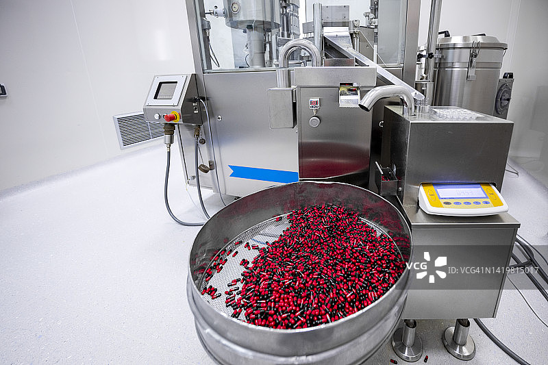 药品生产过程中使用的红色和黑色药丸大筛子图片素材
