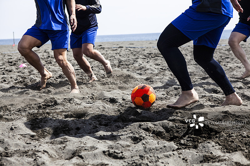 男人在沙滩上踢足球图片素材