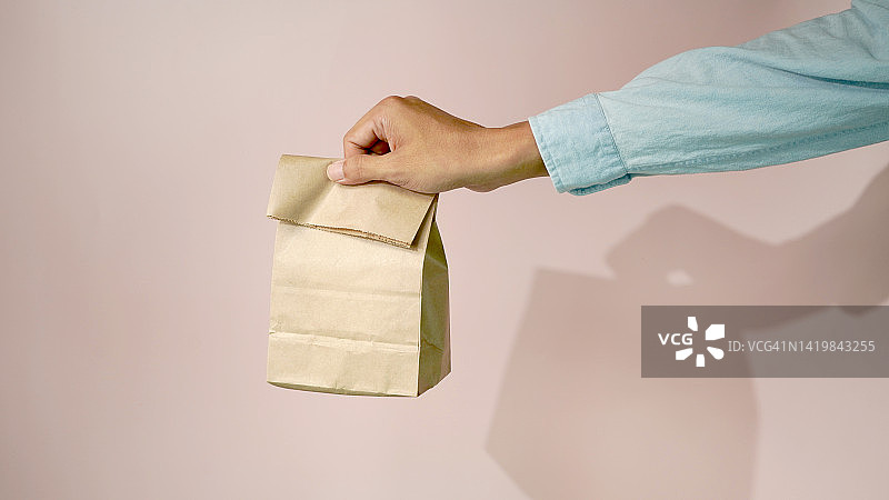 手拿粉色背景外卖纸袋图片素材