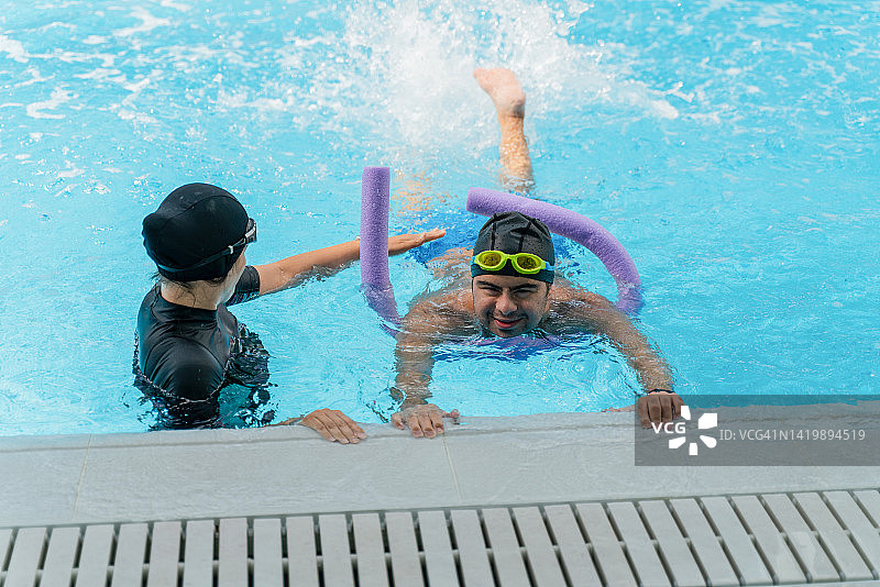 女教练在室内游泳池教唐氏综合征男孩游泳图片素材