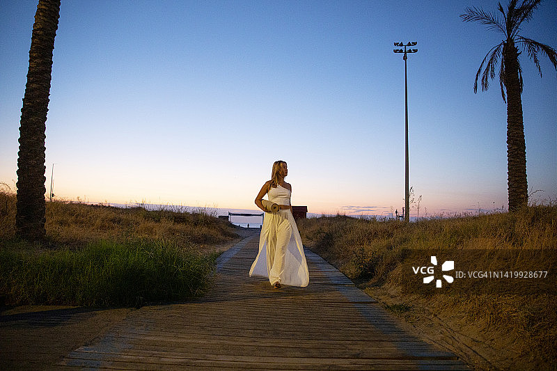 在海滩上手持瑜伽垫看向镜头的女人图片素材