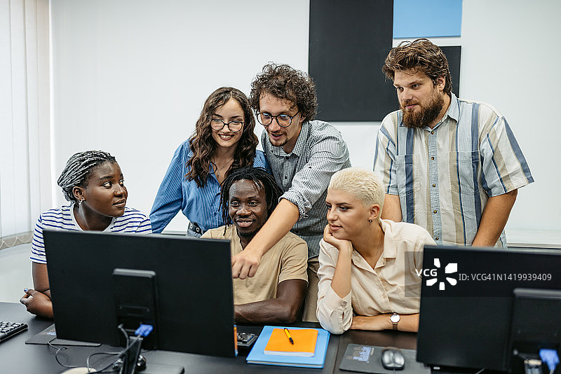 年轻男教师在编程课上帮助学生图片素材
