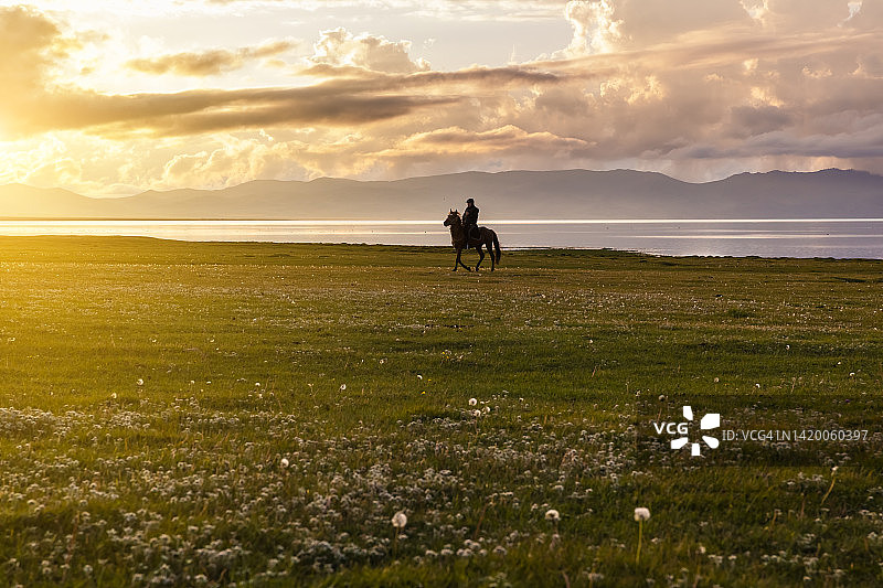 在吉尔吉斯斯坦宋科尔湖岸边日落时分的骑马者图片素材