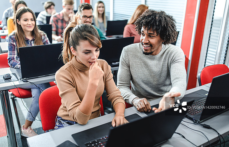 快乐的学生在电脑室用笔记本电脑合作学习图片素材