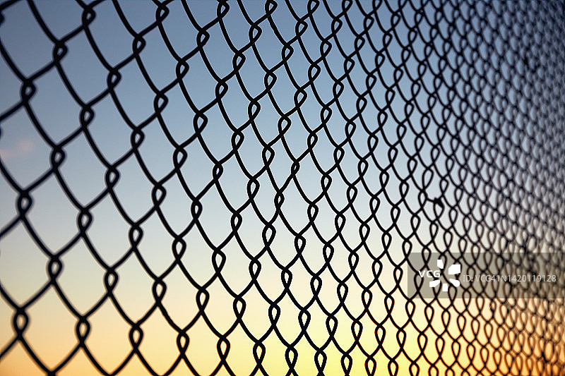 铁丝网映衬夕阳下的天空图片素材