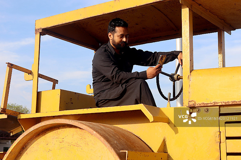 男人驾驶压路机并使用手机图片素材