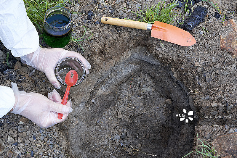 研究人员拿着一把勺子，里面有用于土壤分析的样本图片素材