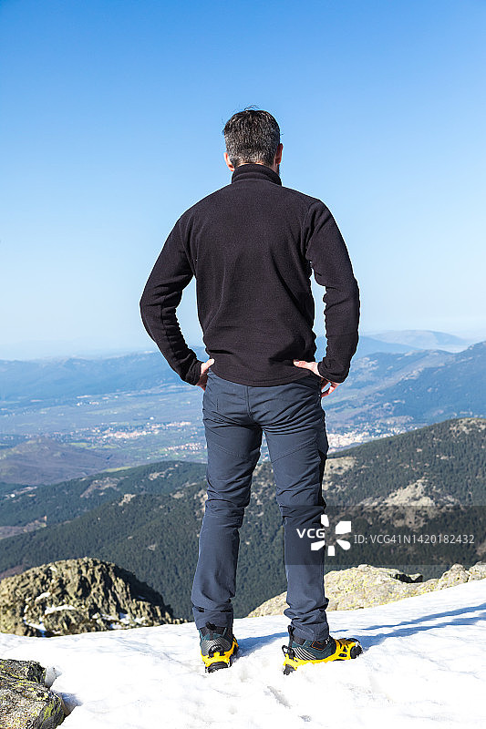 登山者穿着靴子和冰爪，踩在雪地上，攀登锹形山峰。登山、探险、挑战、危险图片素材