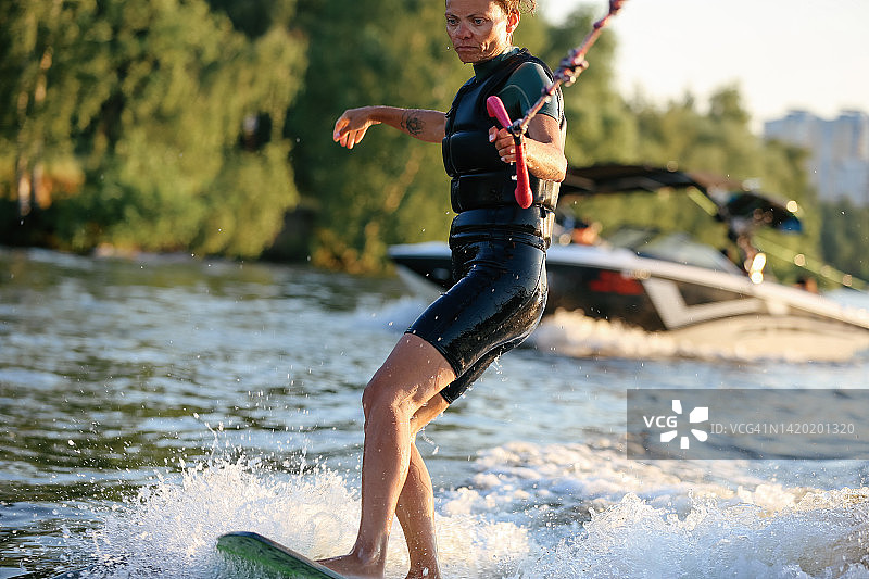 在河上进行尾波冲浪训练的年轻漂亮女人图片素材