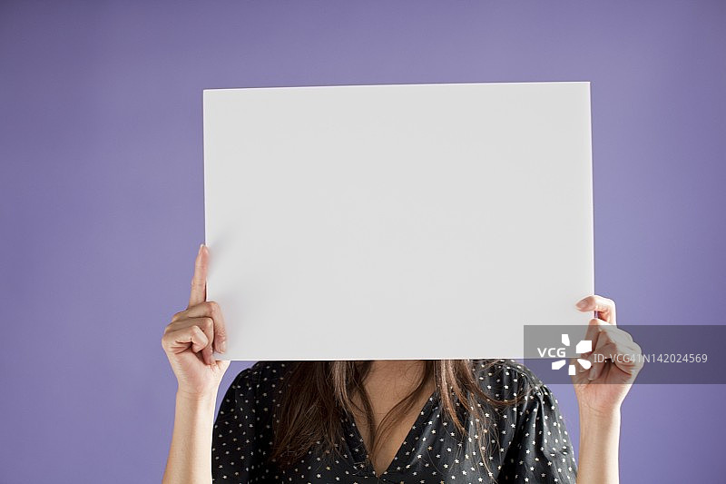 女人举着遮住脸的空白板图片素材
