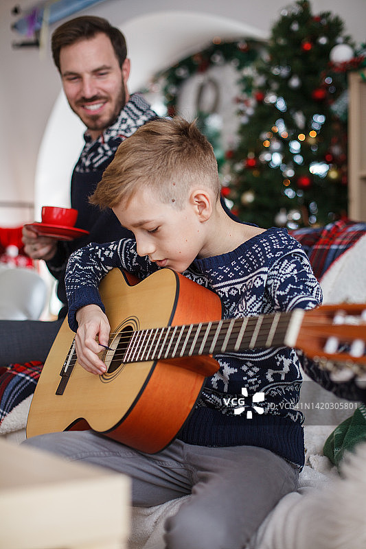 在圣诞节练习原声吉他的青少年男孩图片素材
