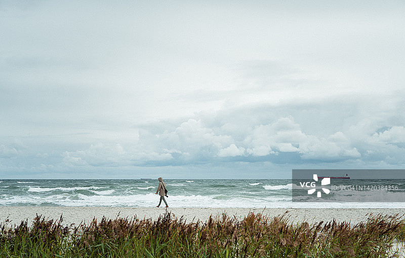 在沙滩上走过远处沙丘的年轻男人图片素材