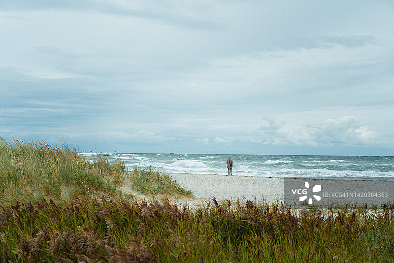在沙滩上走过远处沙丘的年轻男人图片素材
